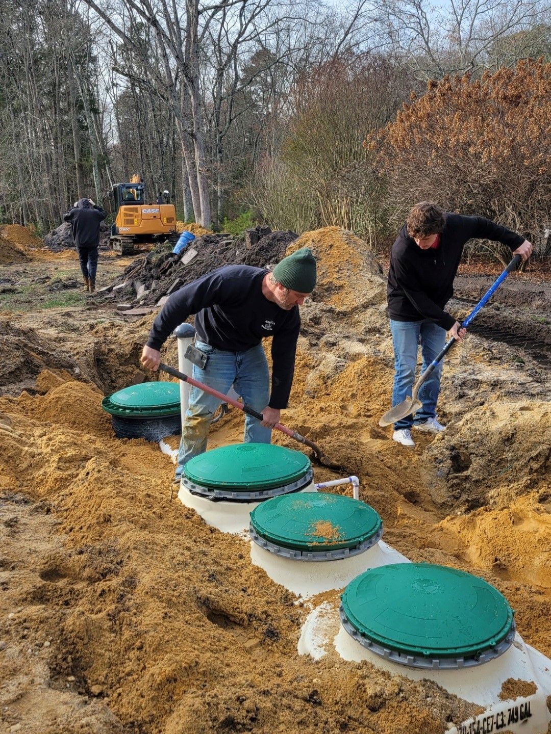 A man is opening a green manhole cover on a septic tank.