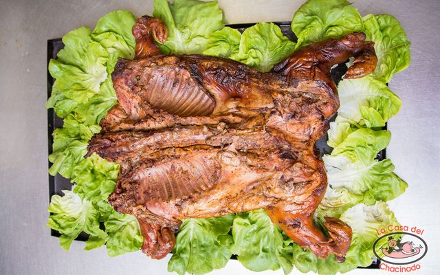 Pescado entero a la parrilla sobre hojas de lechuga, dorado y servido en una bandeja.