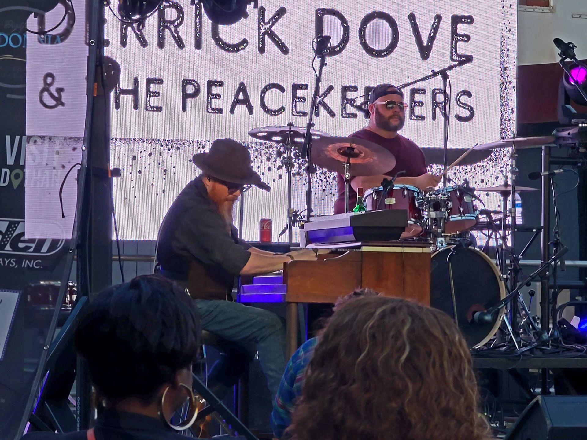Keyboardist & drummer on stage under a banner that says 