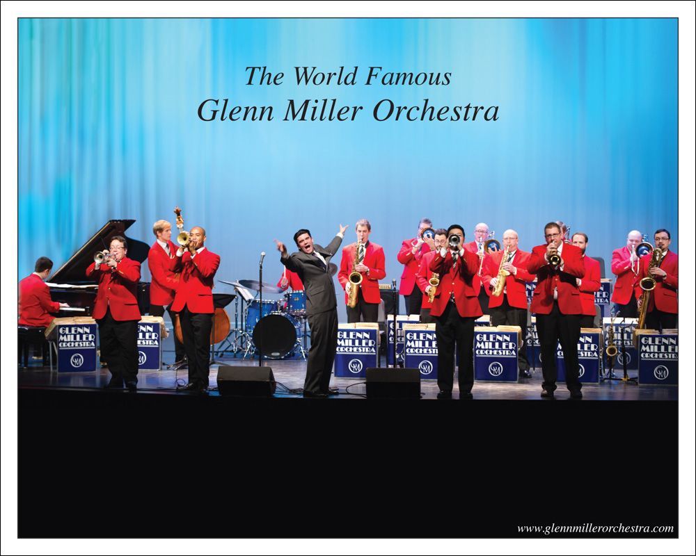 Glenn Miller Orchestra on stage in red jackets, performing with a singer.
