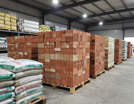 Corridoio del magazzino con mattoni impilati su pallet e sacchi di materiali edili