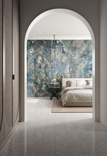 Corridoio ad arco che si apre su una camera da letto minimalista con una parete decorata con un murale blu-verde.