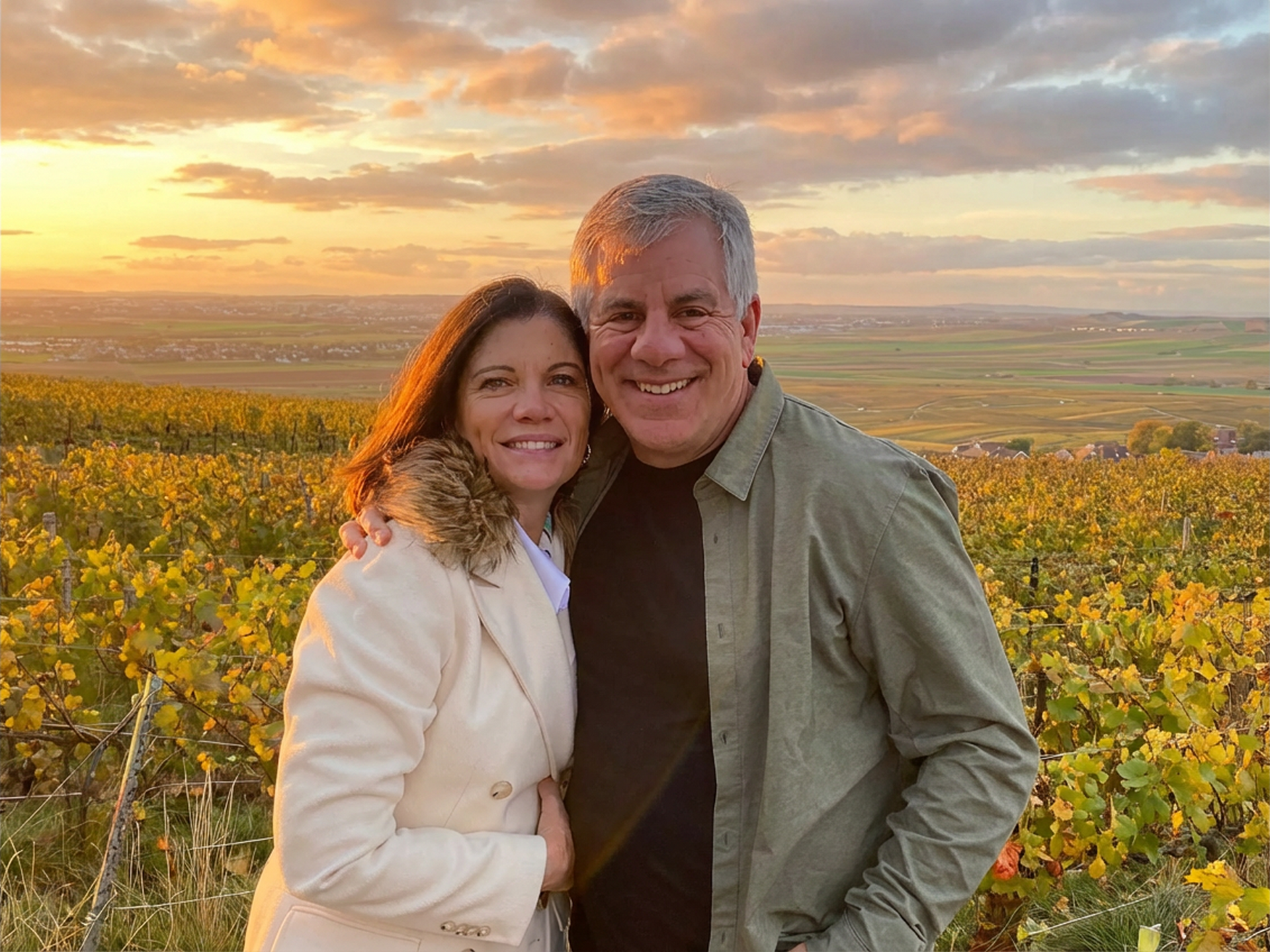 Couple embracing in a vineyard at sunset; fields, golden light.