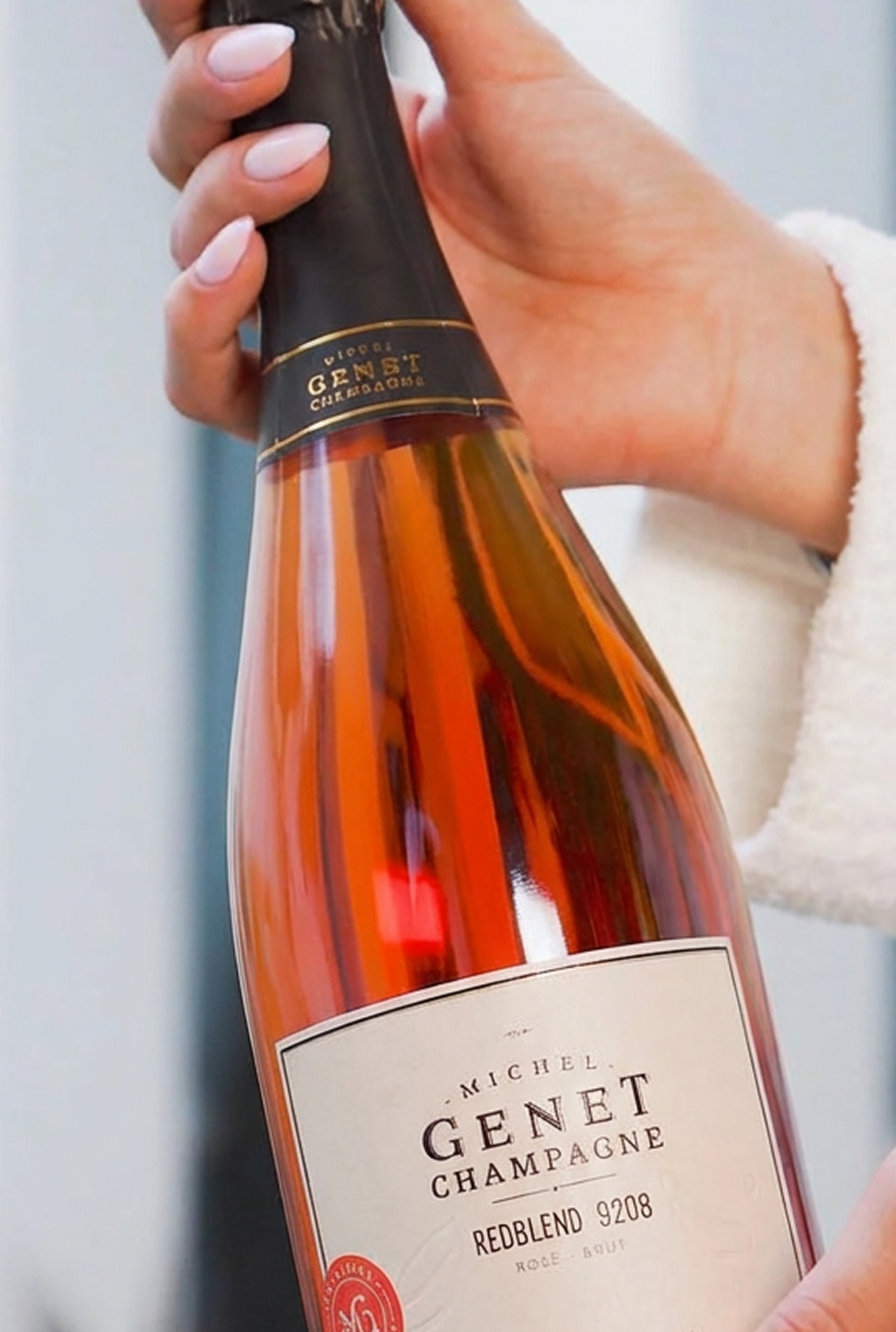 Person holding a bottle of pink champagne.