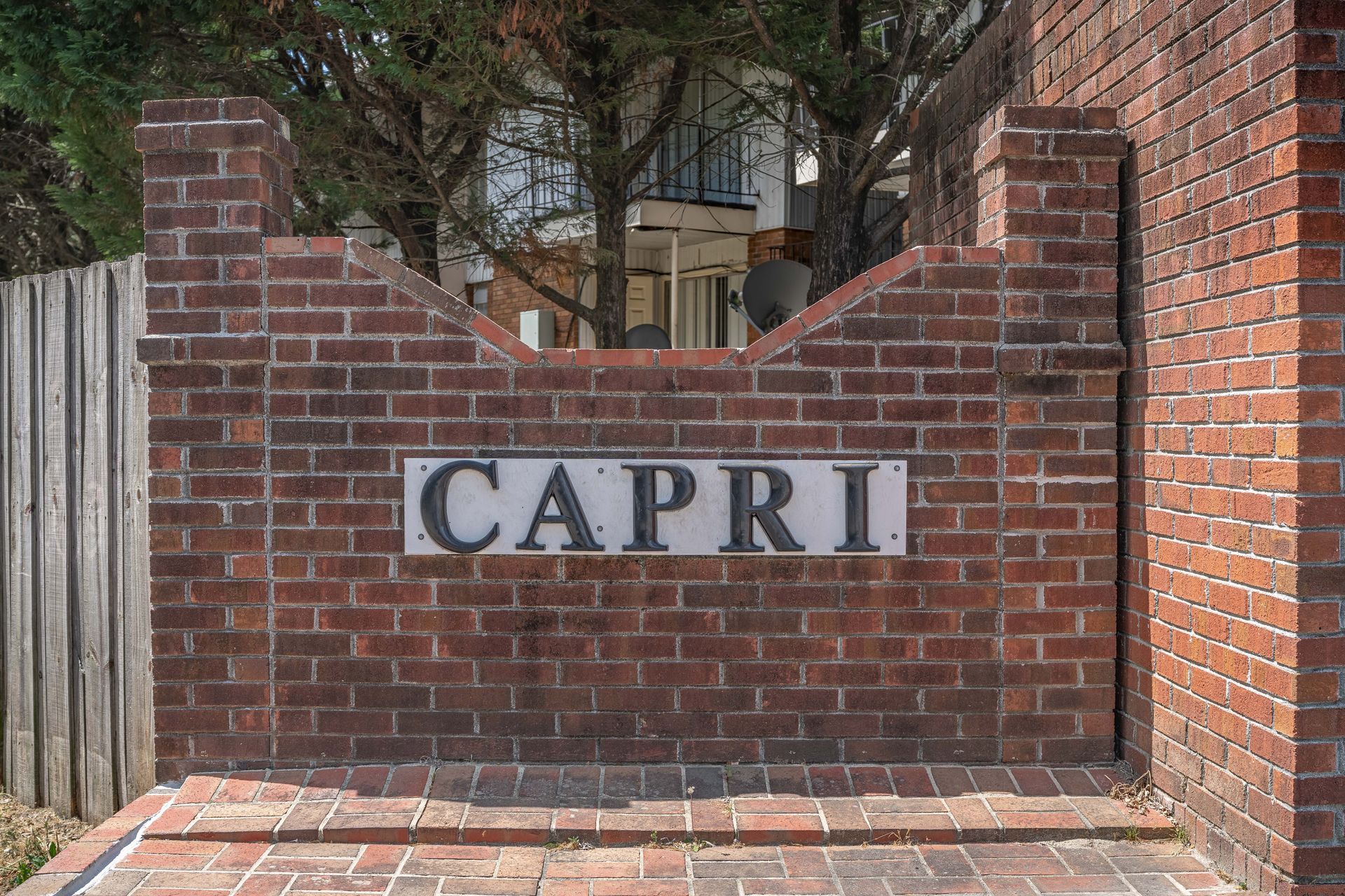 A brick wall displaying a rectangular sign with the word 
