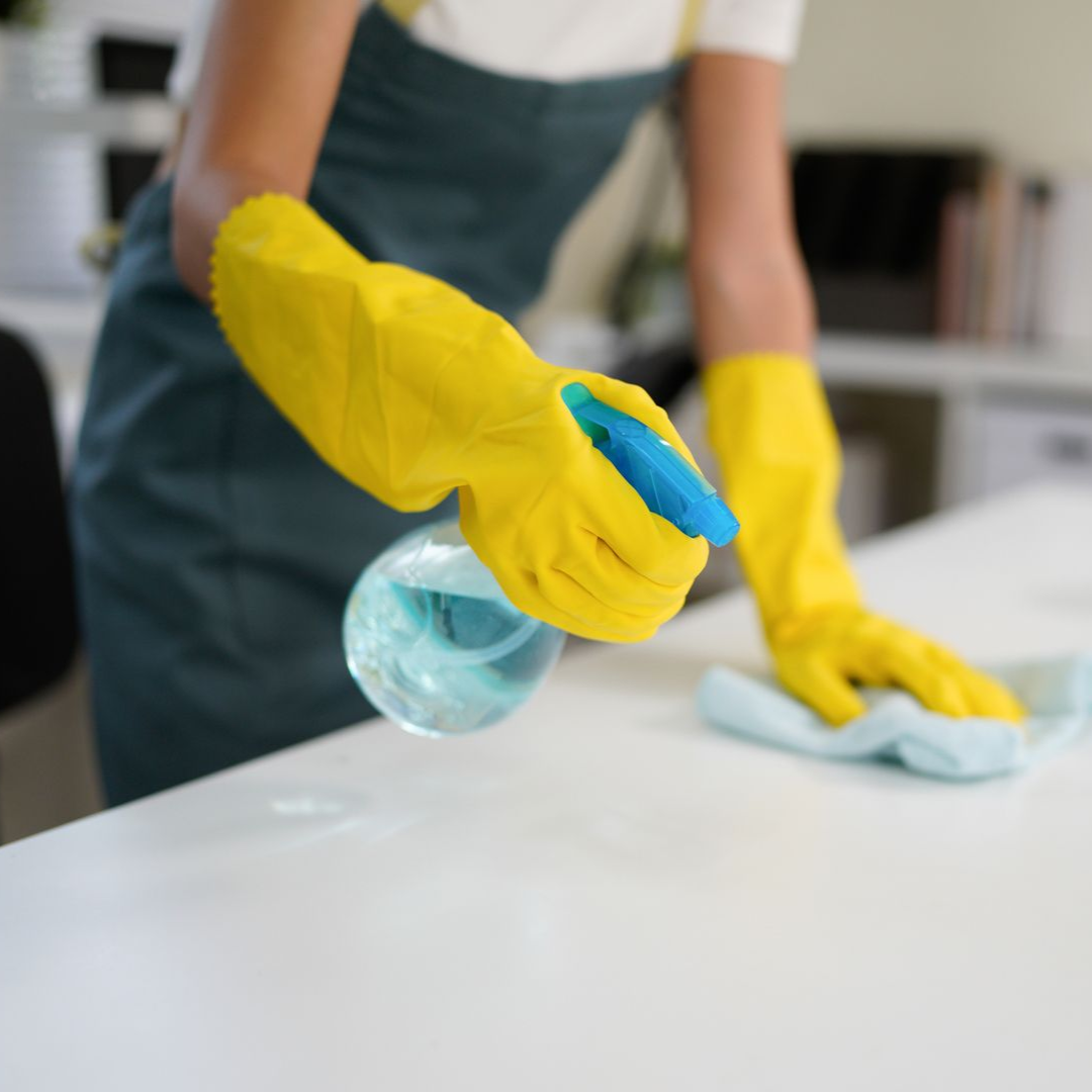Person in blue cleaning uniform mopping a hallway with a bucket on wheels.
