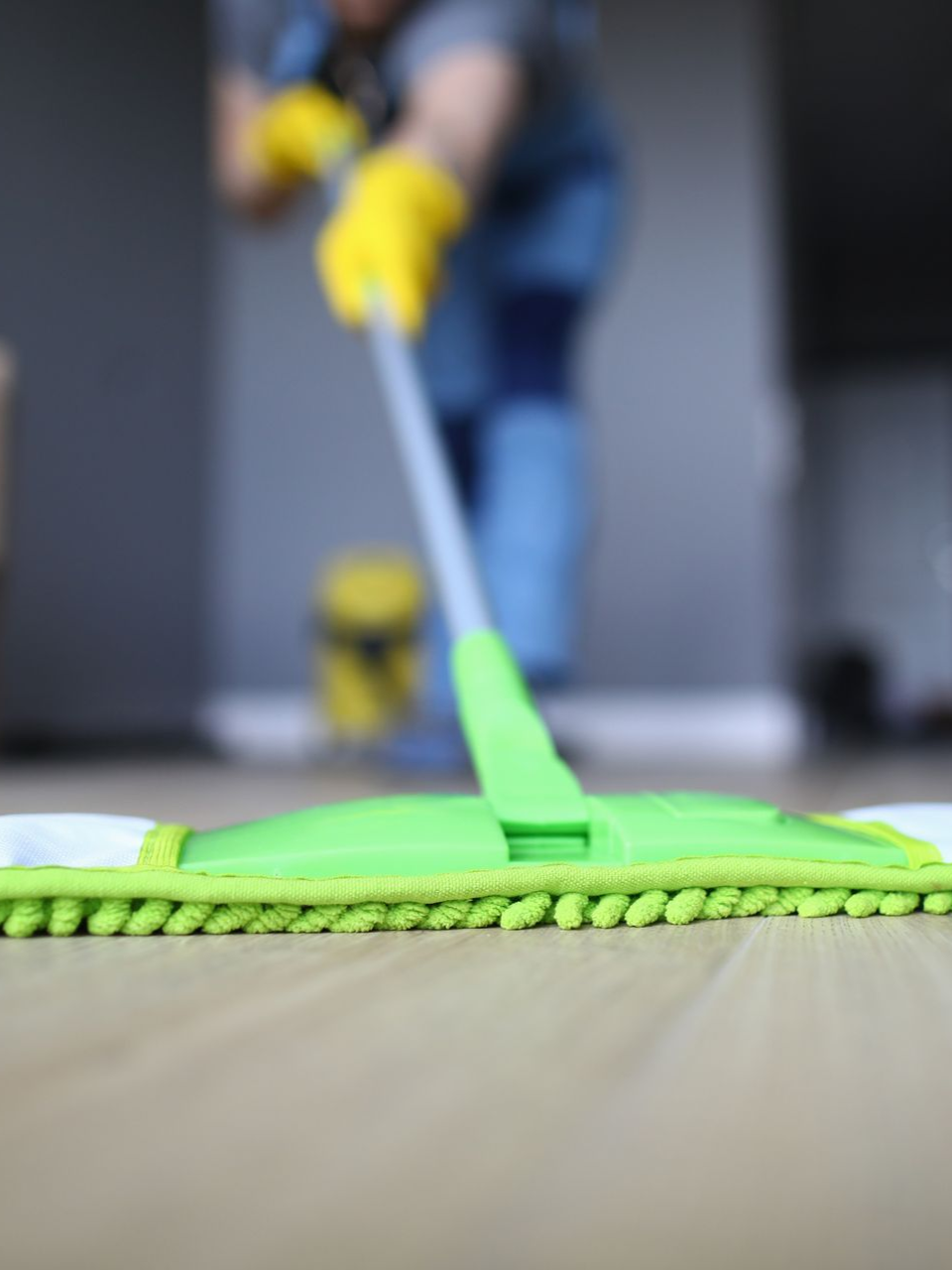 Person wearing blue gloves, cleaning a surface with a spray bottle in an office setting.