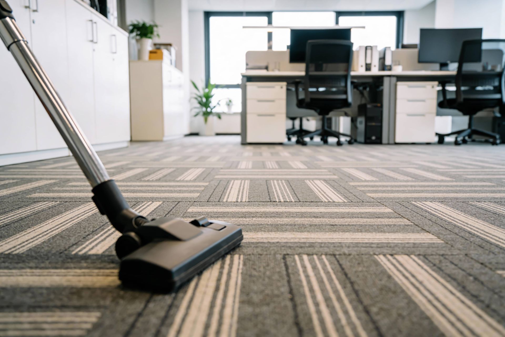 Vacuum cleaner on striped office carpet in a bright, modern workspace