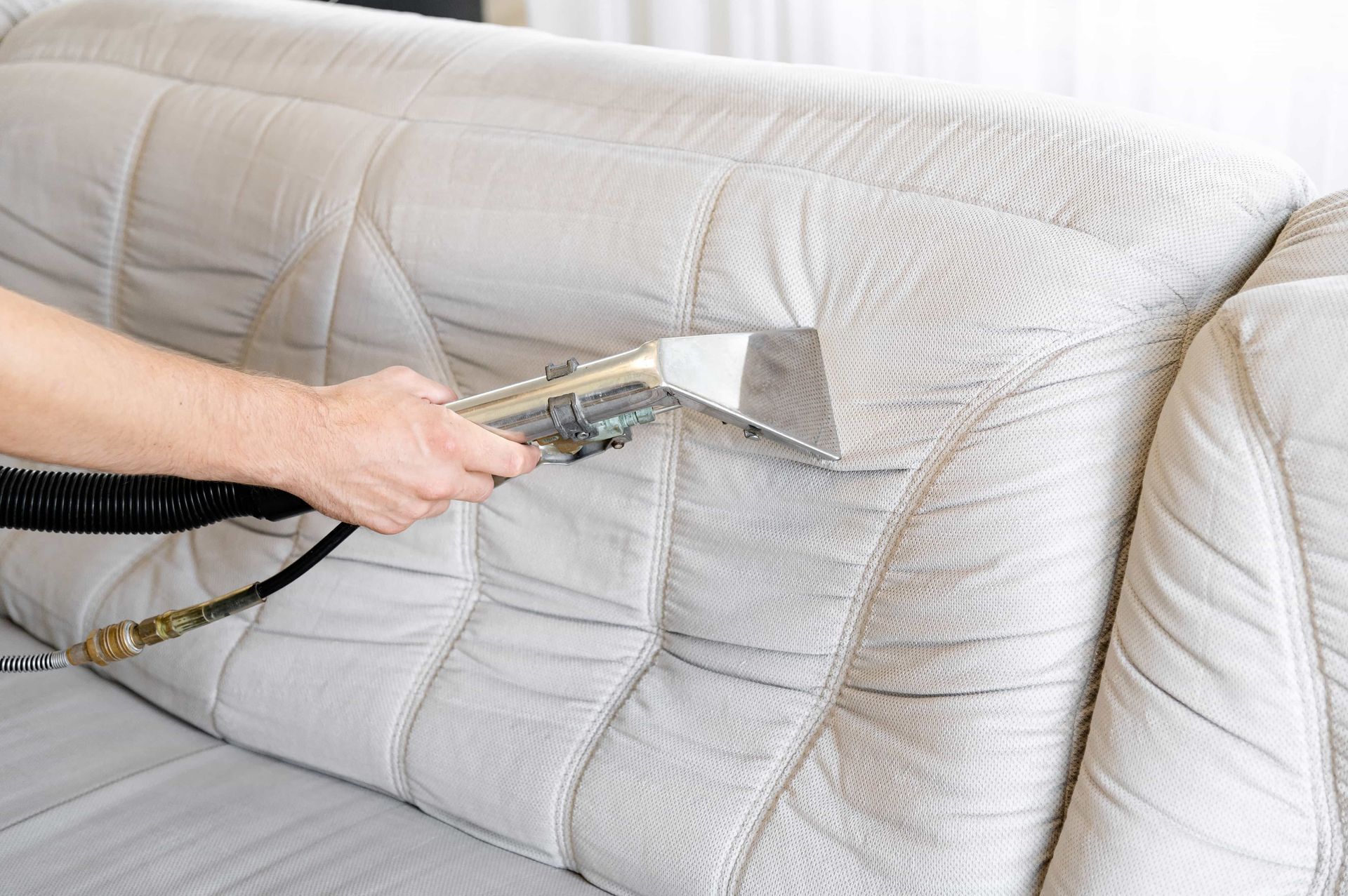 Steam cleaner removing stains from a beige couch cushion
