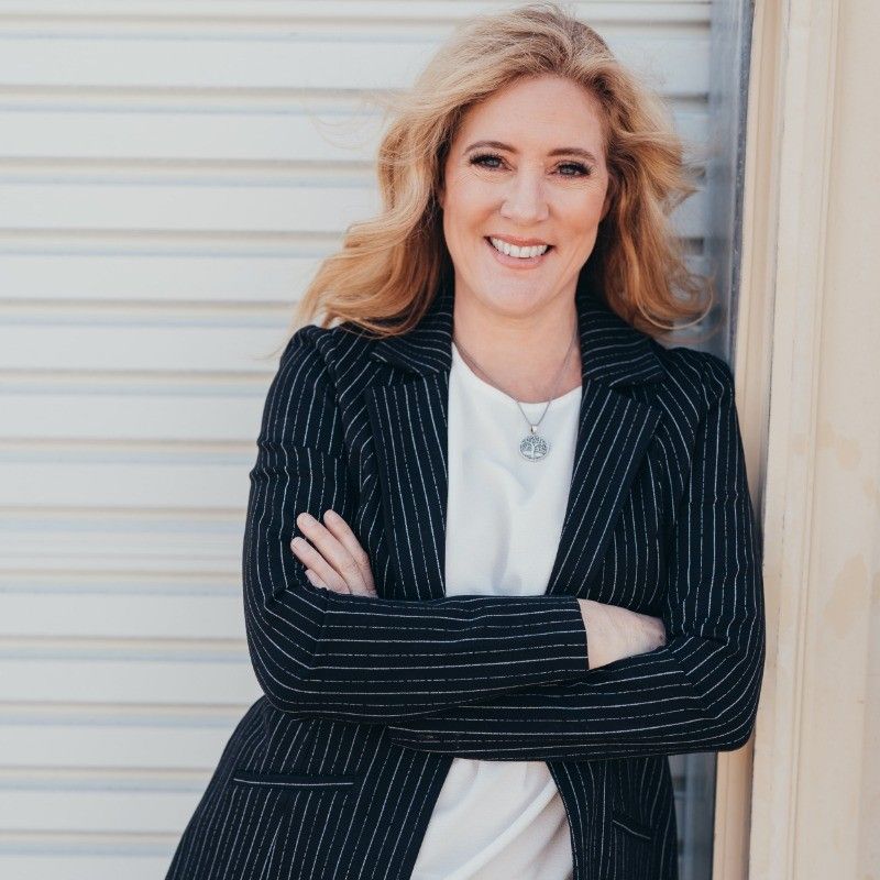 A woman in a black and white striped jacket is smiling with her arms crossed