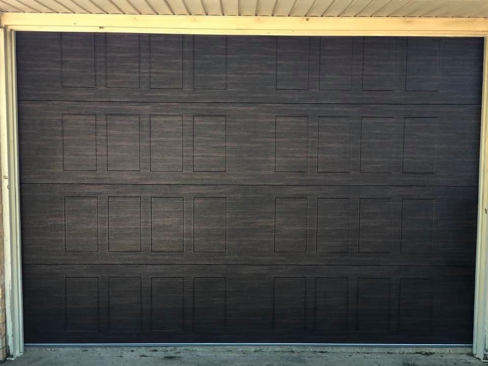 Dark brown garage door with rectangular panels, in a white frame.