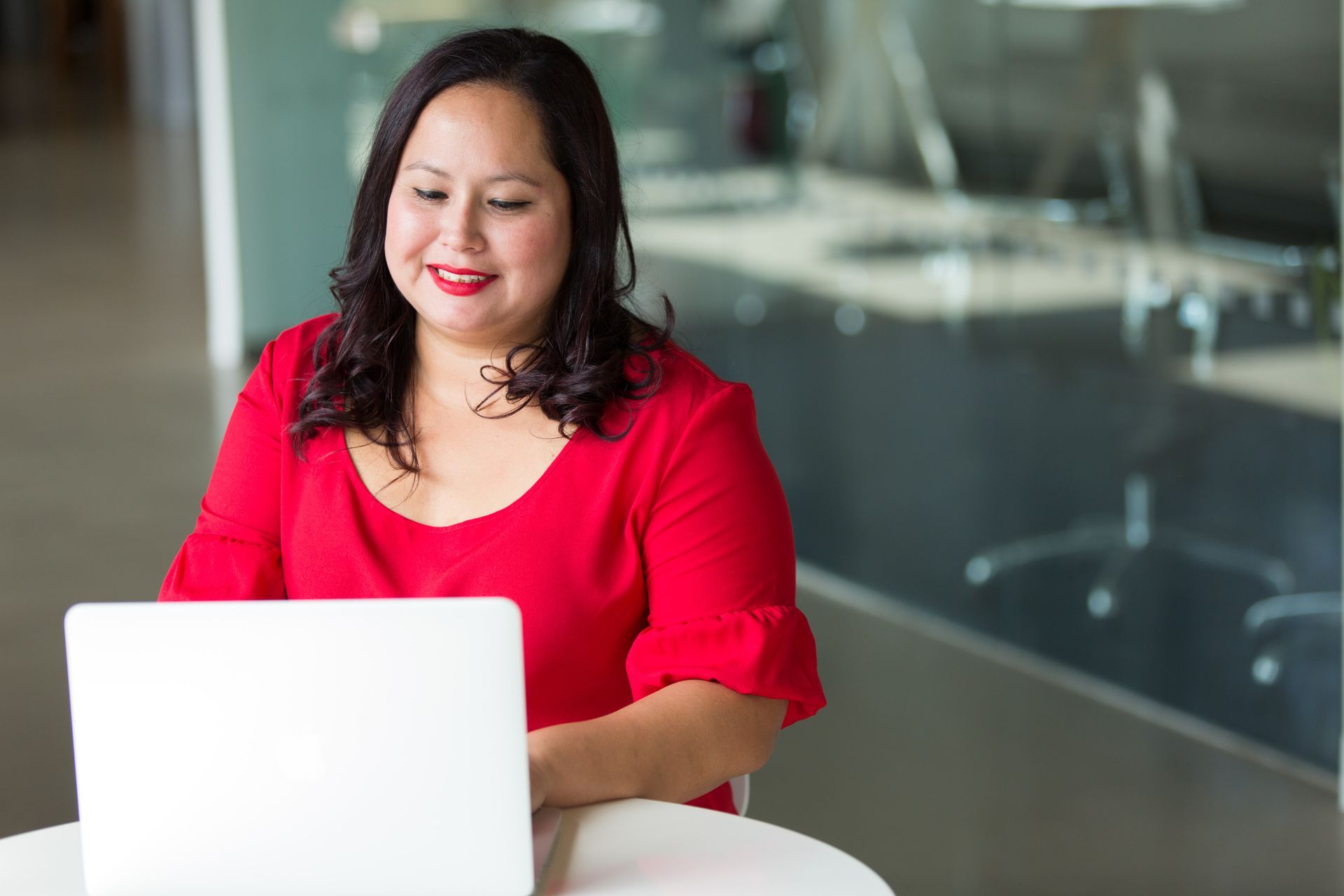 Professional woman in red top in front of a laptop