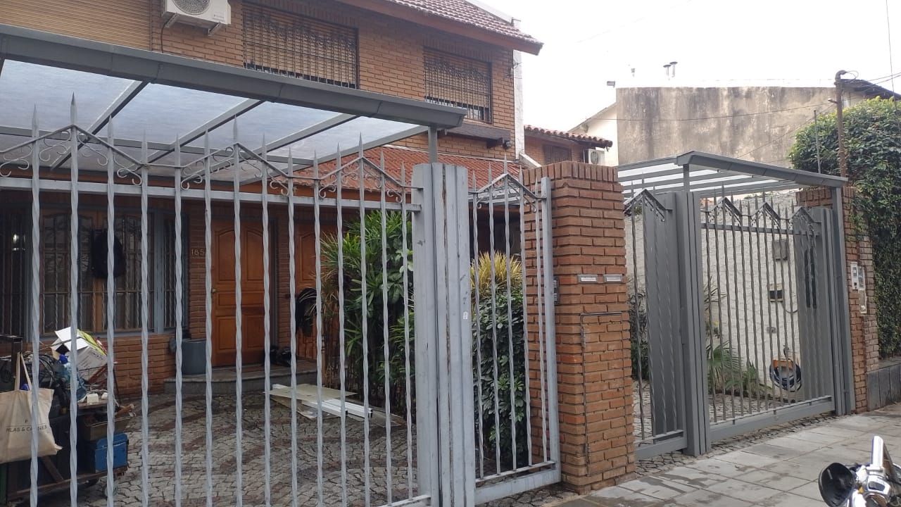 Una motocicleta está estacionada frente a una casa con una valla.