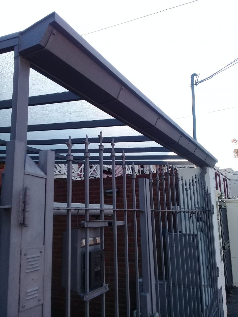 Un edificio de ladrillo con una valla metálica y un techo