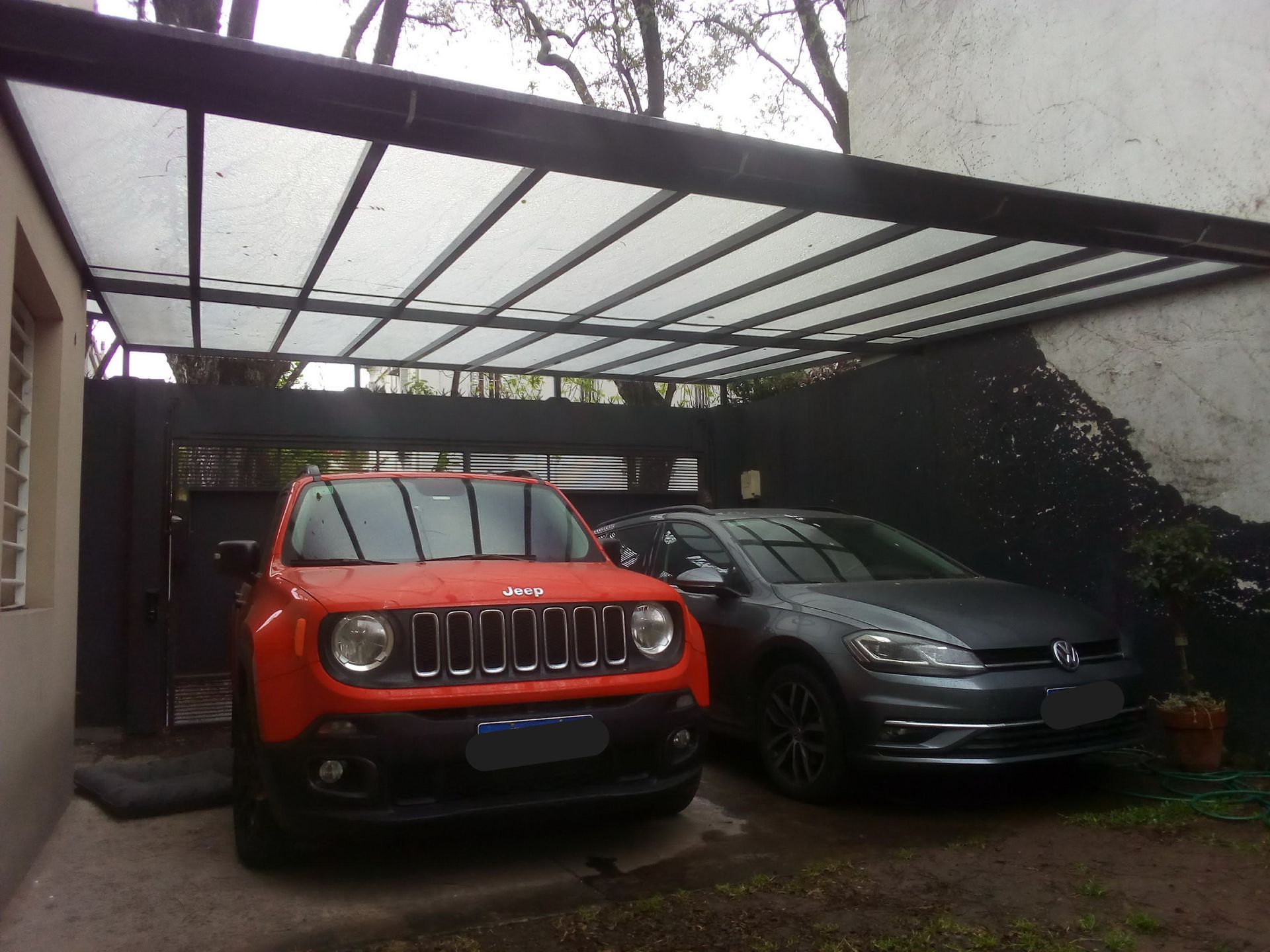Un jeep y un Volkswagen están estacionados bajo un toldo.