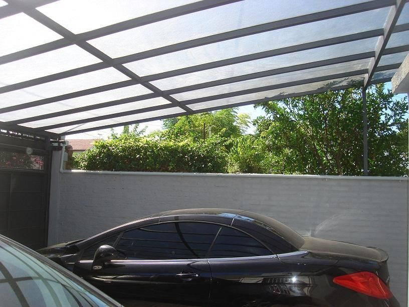 Un coche negro está aparcado bajo un toldo en una entrada.