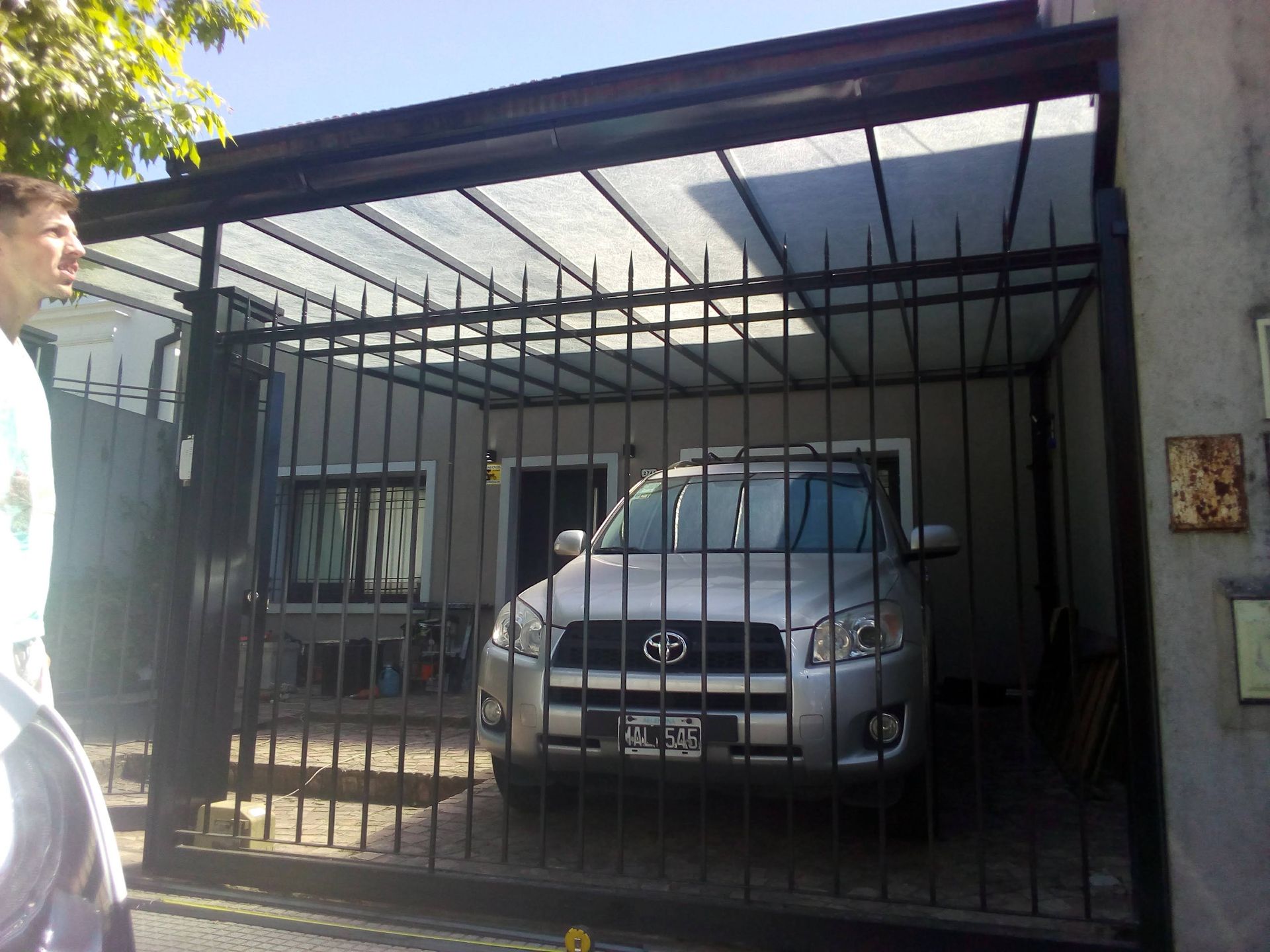 Un Toyota plateado está estacionado en una entrada cercada.