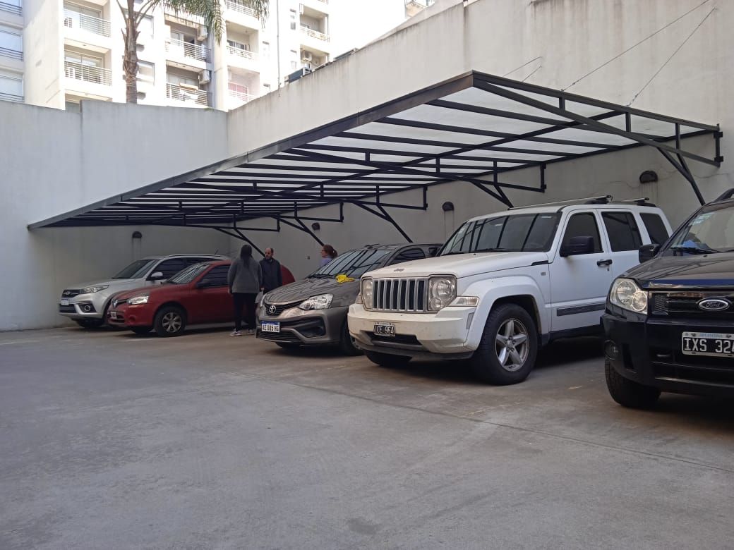 Un techo de garaje de edificio protejiendo 5 coches.