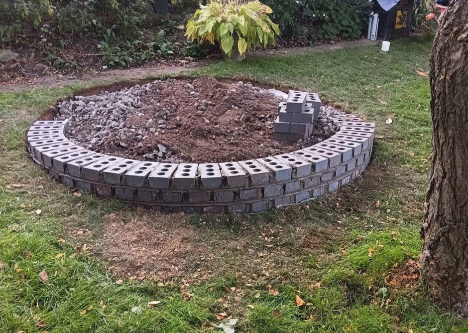 A ring of bricks built on the lawn with the stone base going in