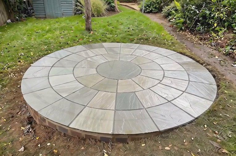 Circular sandstone patio set as a feature in a lawn in Kenilworth