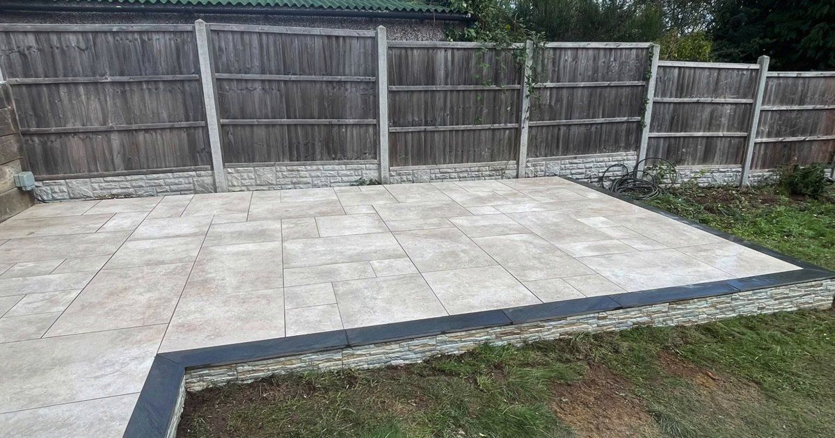 Raised cream porcelain patio with anthracite copings in a back garden in Earlsdon