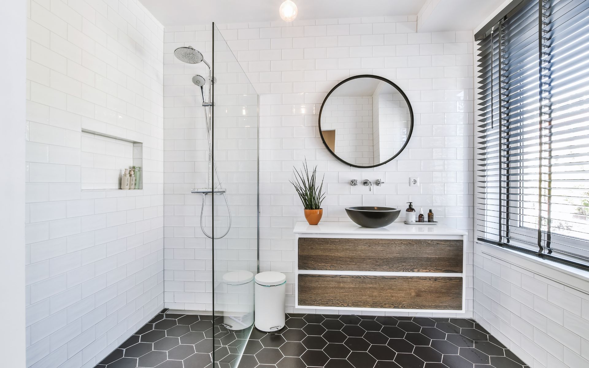 a bathroom with a walk in shower , sink , mirror and window .