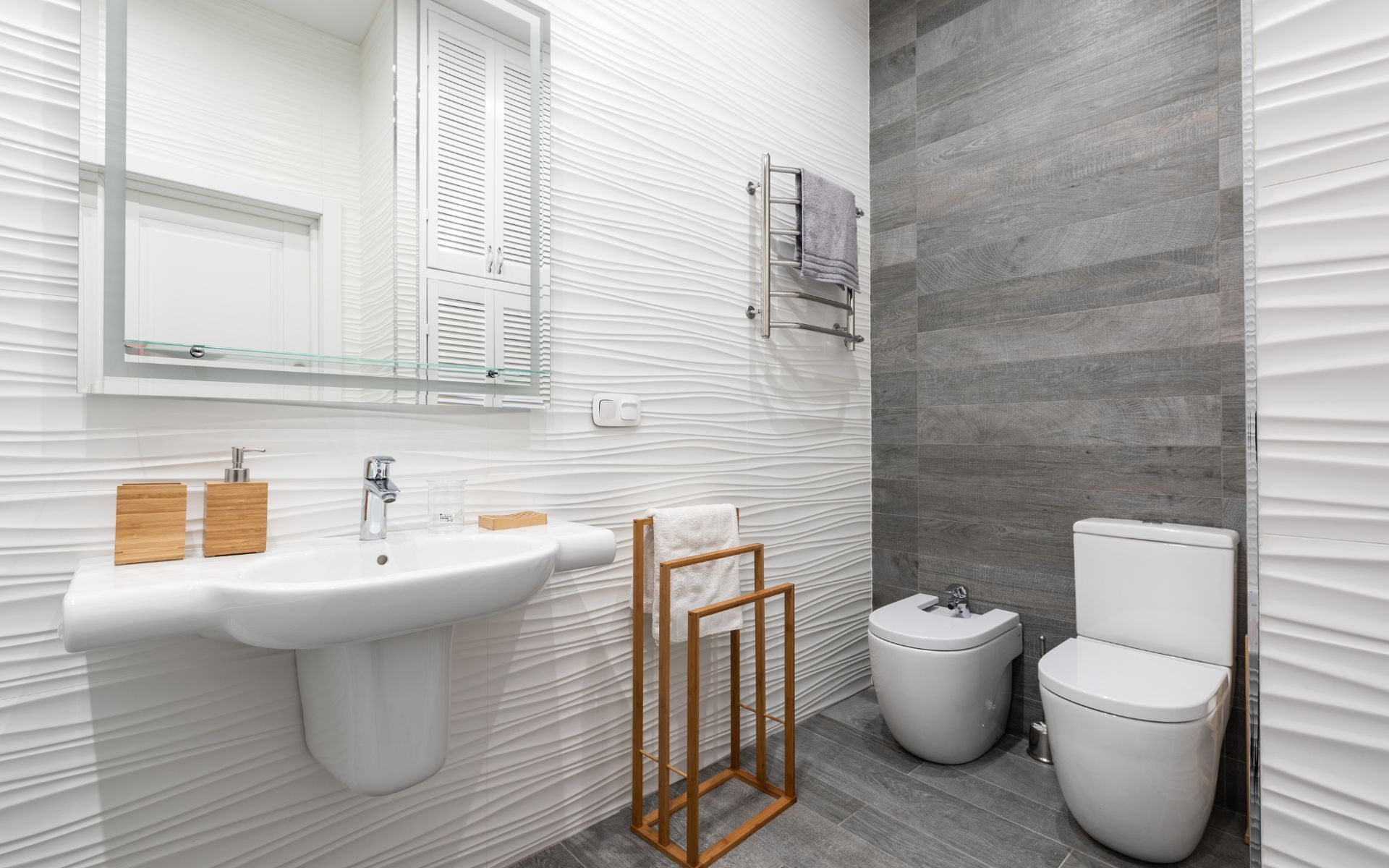 a bathroom with two toilets , a sink and a mirror .