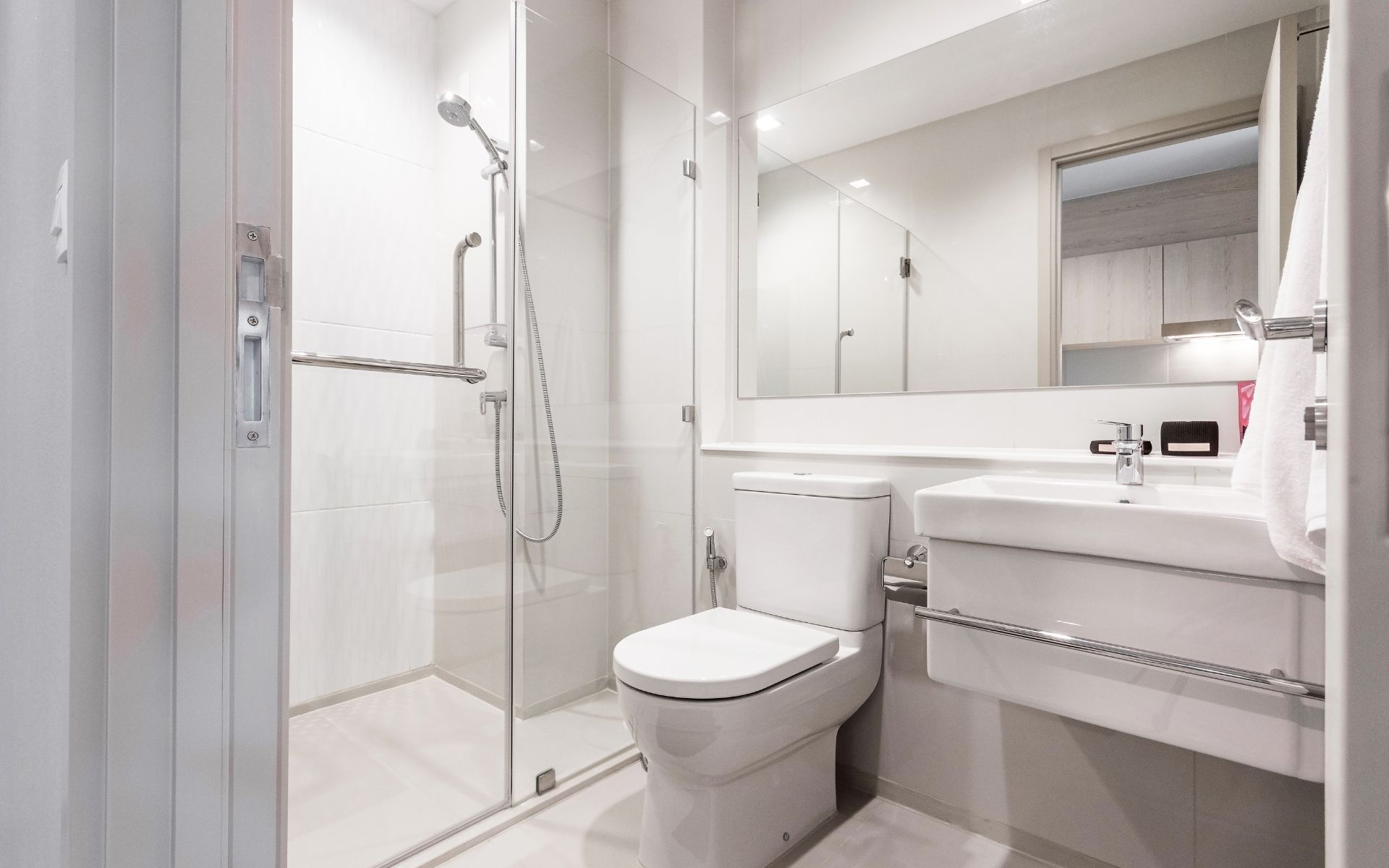 a bathroom with a toilet , sink , shower and mirror .