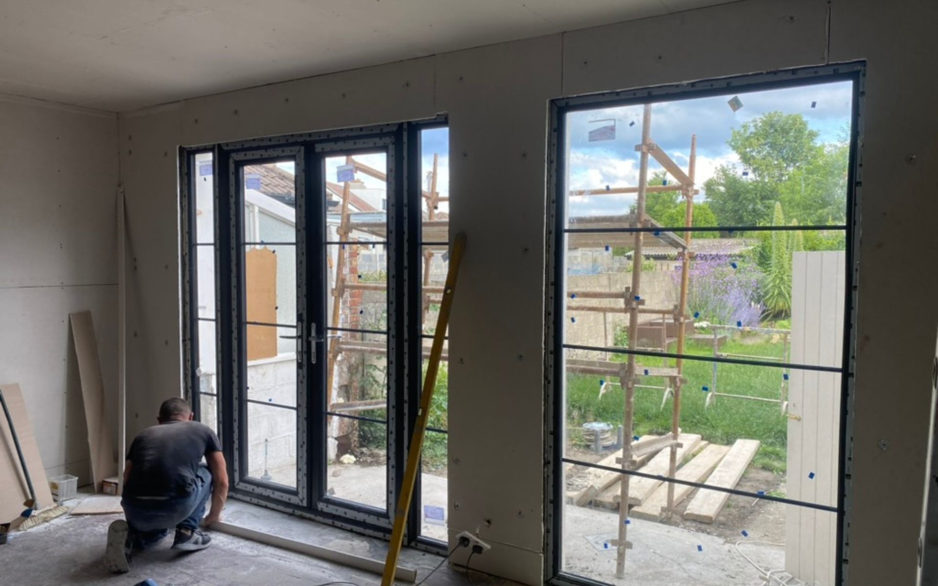 a man is kneeling down in a room with a lot of windows .