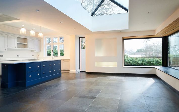 an empty kitchen with blue cabinets and a large window .