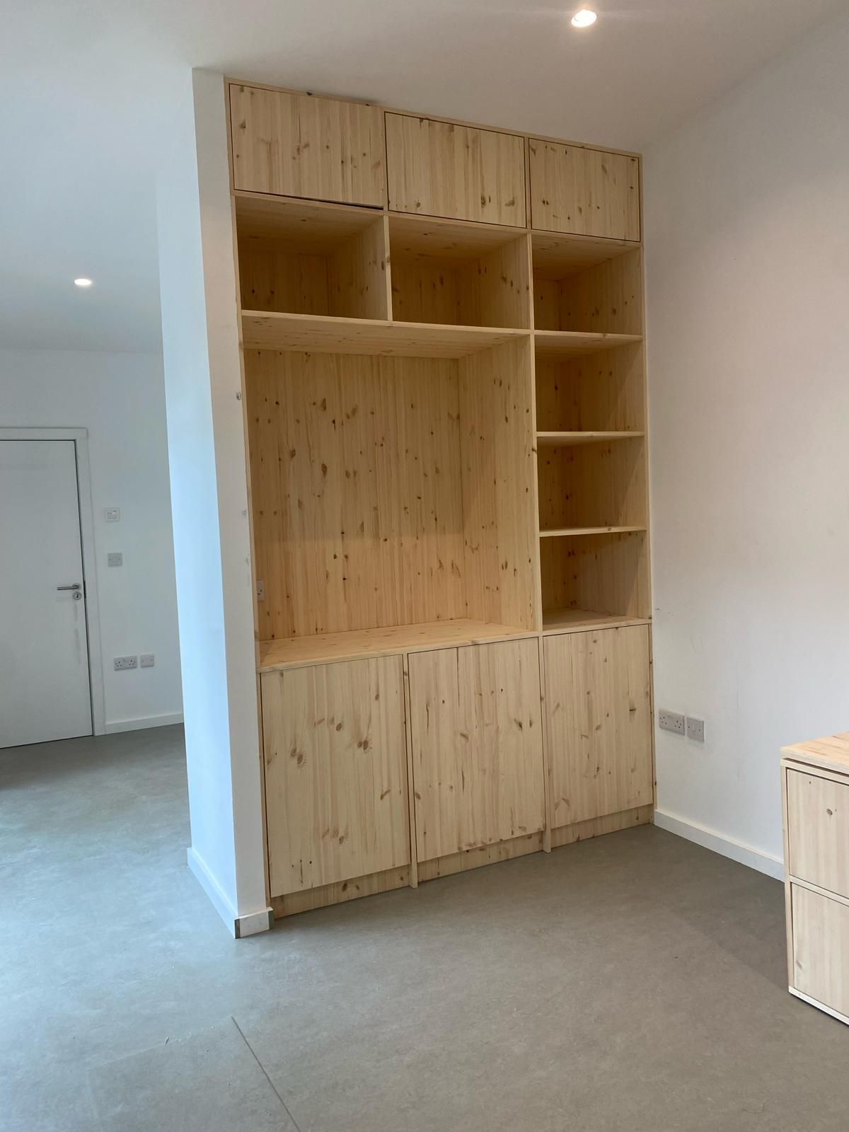 there is a large wooden shelf in the middle of the room .