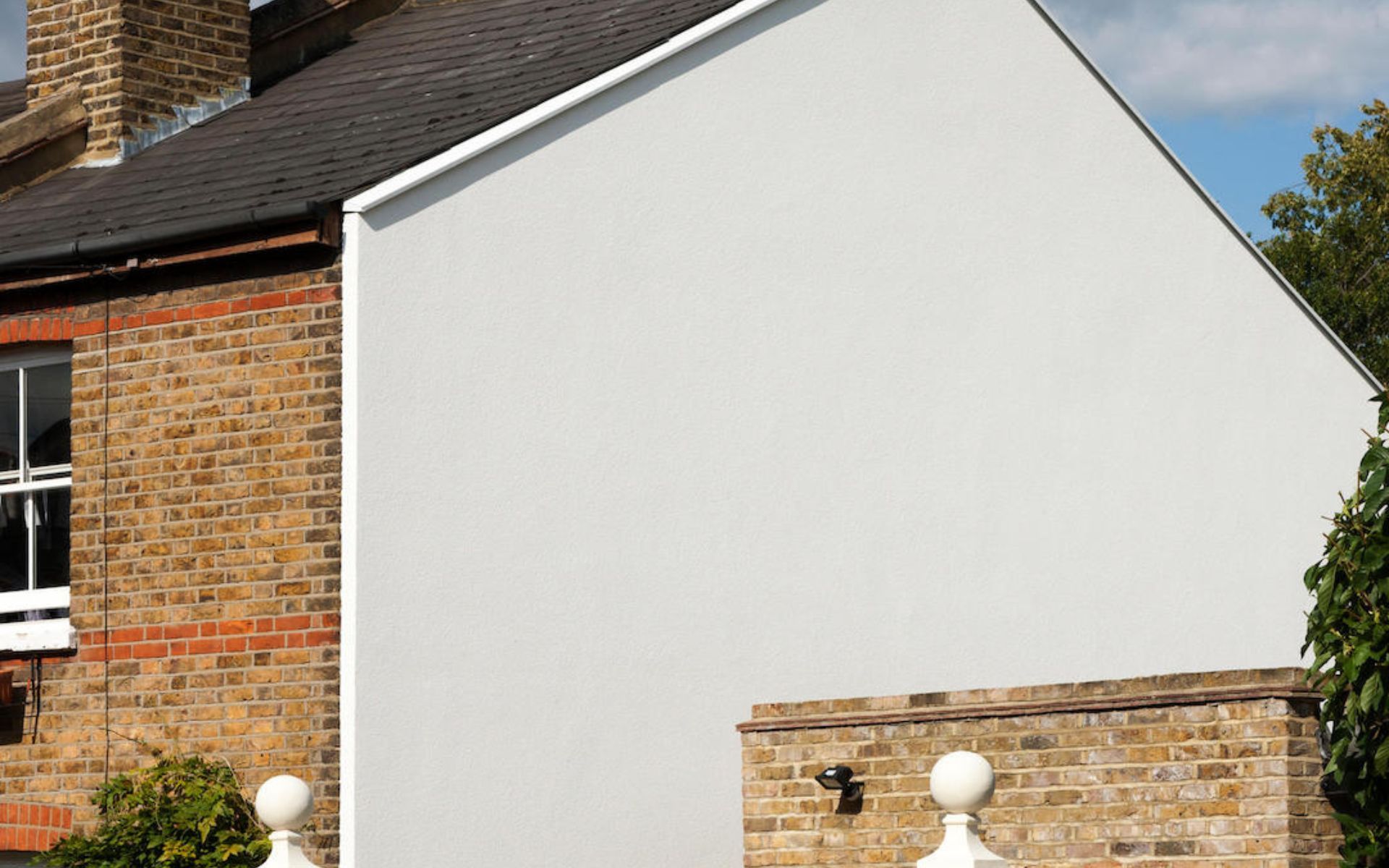 a white house with a brick wall and a chimney on the roof .