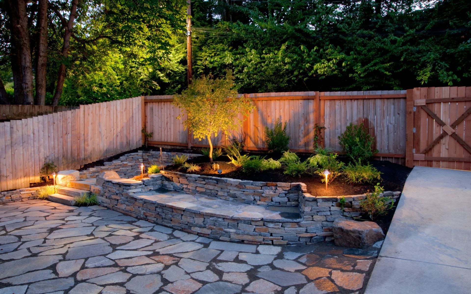 a backyard with a stone patio and a wooden fence .