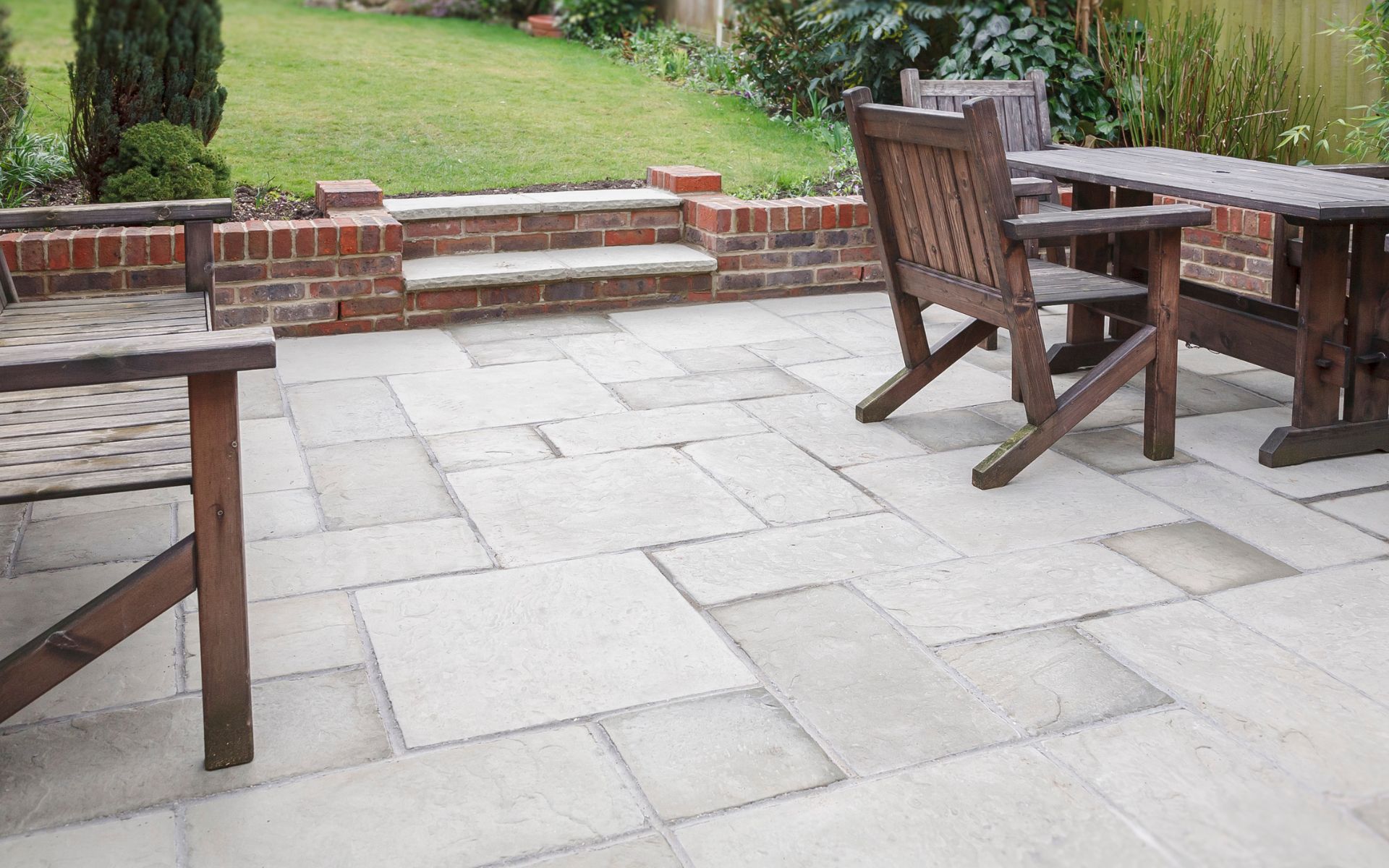 a stone patio with wooden chairs and a table