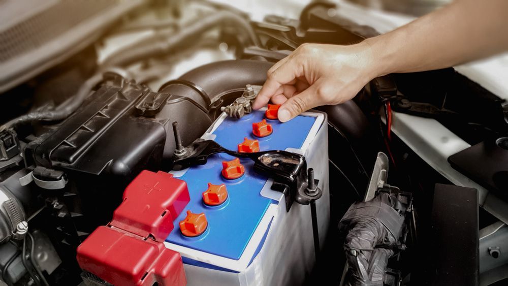 A Person Is Plugging A Battery Into A Car — Chris's Automotive & Marine Electrics In Marlow Lagoon, NT