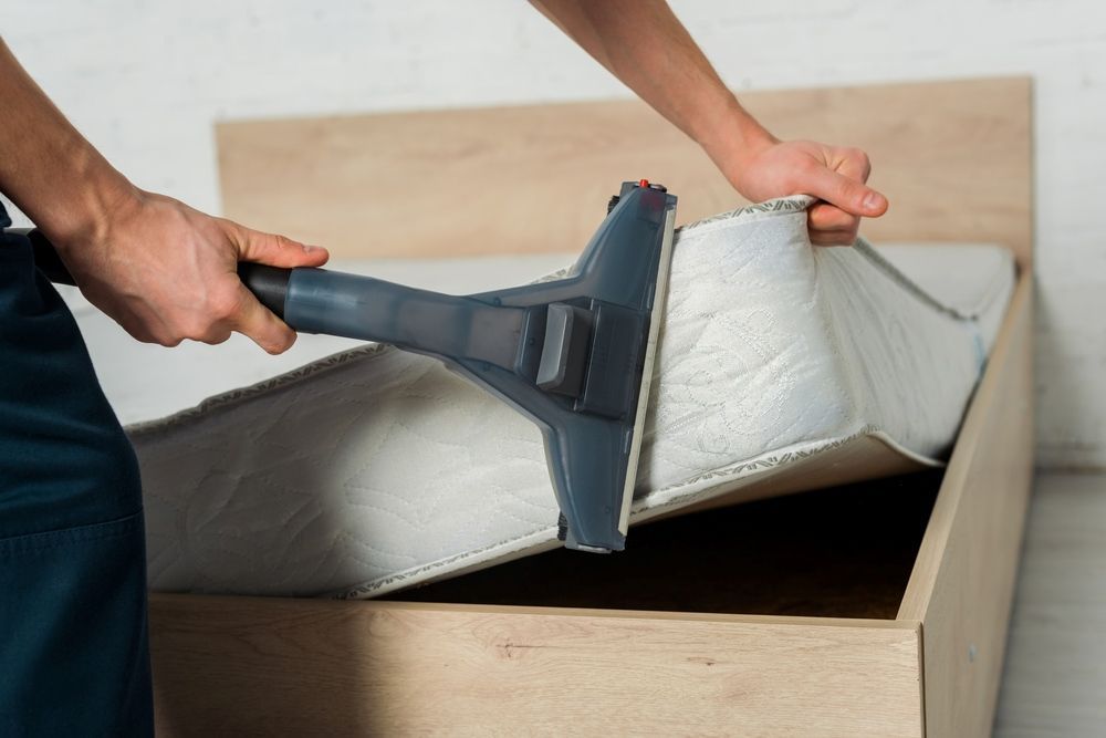 A Person Is Cleaning A Mattress With A Vacuum Cleaner — Tailored Services in Proserpine, QLD