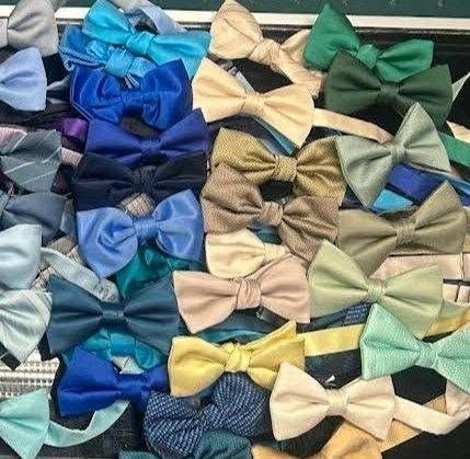 Assorted colorful bow ties arranged in a pattern on a textured surface.