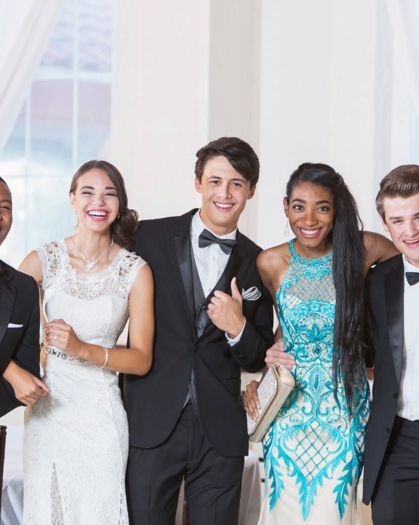 Group of smiling formalwear-clad people posing at a wedding or celebration