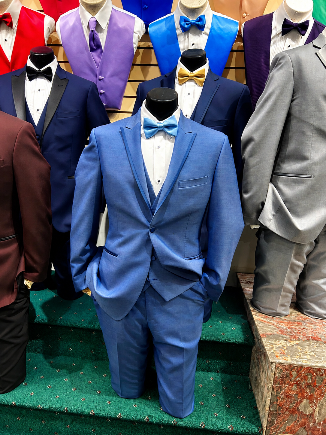 Measuring tape around a black suit jacket on a mannequin, with a hand adjusting the lapel