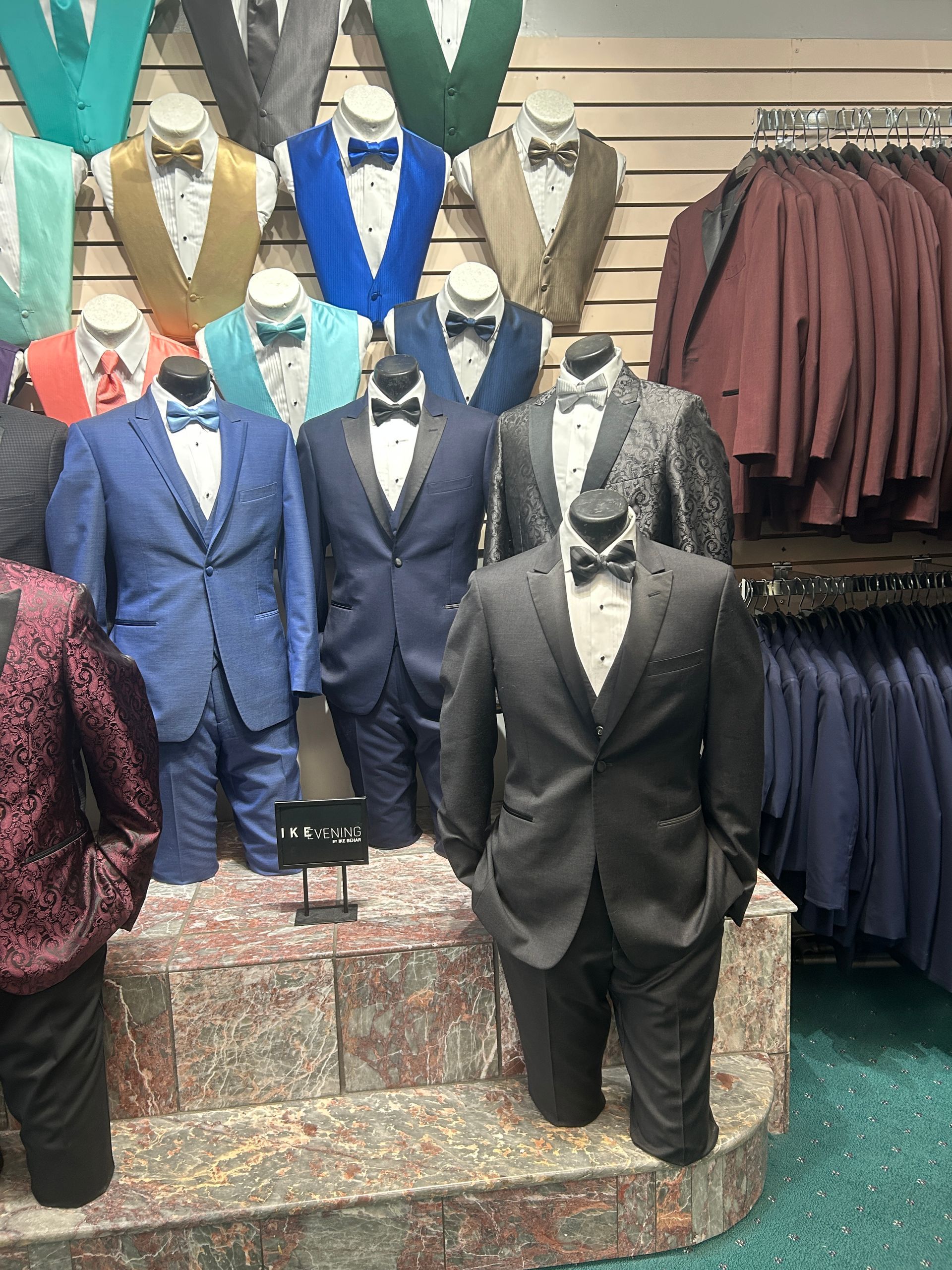 Suits and tuxedos on mannequins displayed in a formalwear shop