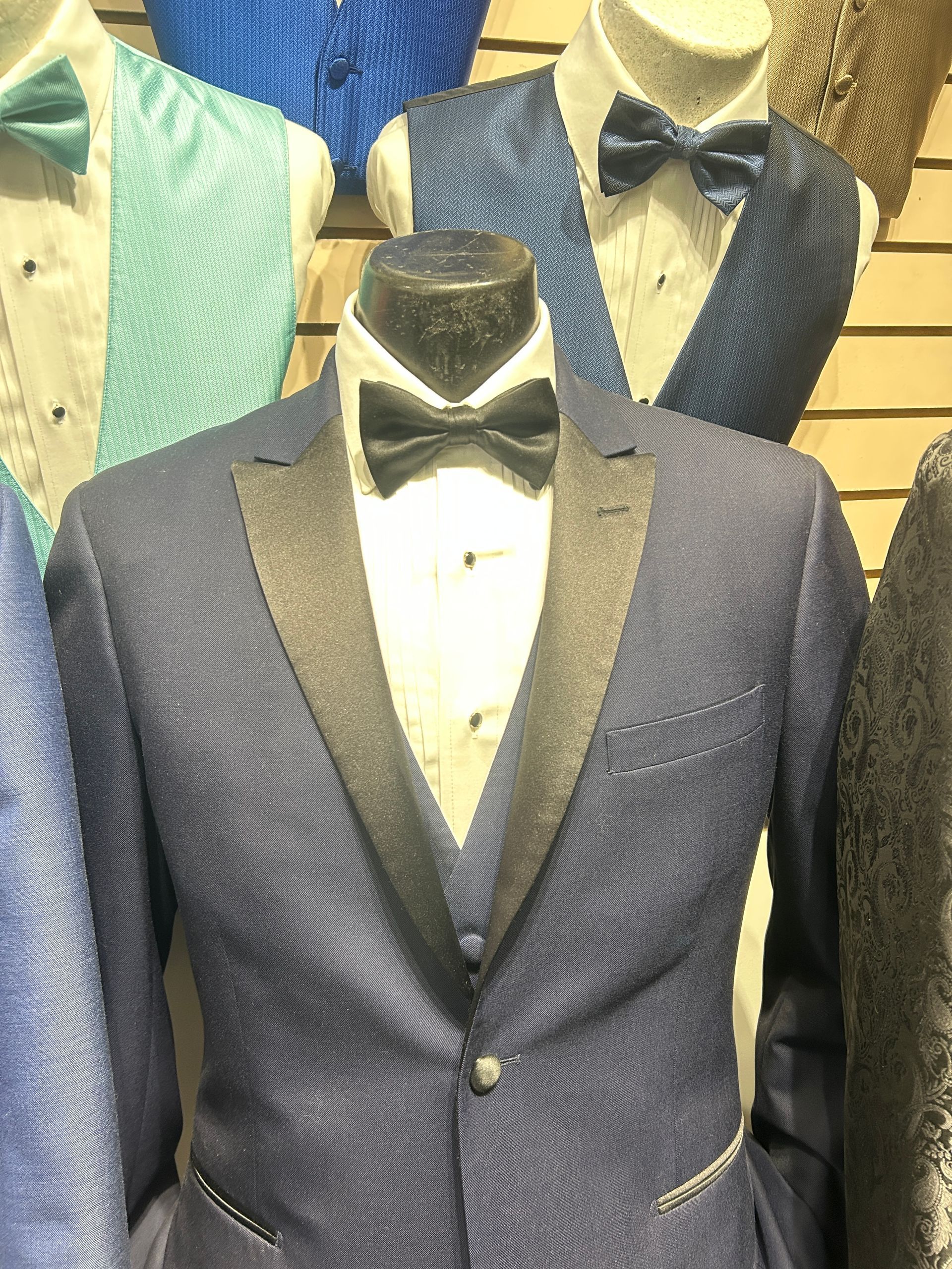 Mannequins wearing formal tuxedos and suits in a clothing store display