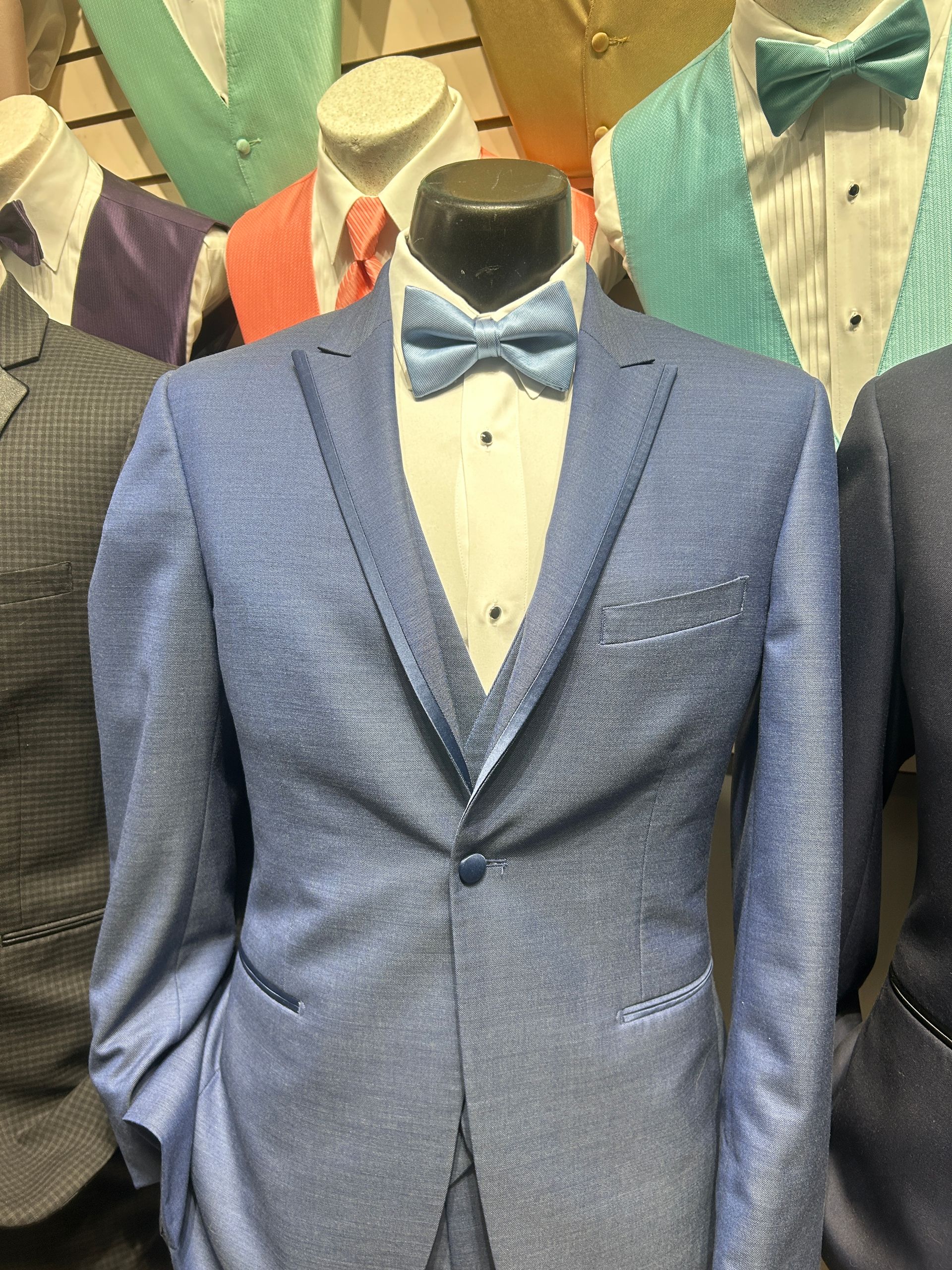 Light blue tuxedo jacket with matching bow tie and white shirt on a mannequin among suits