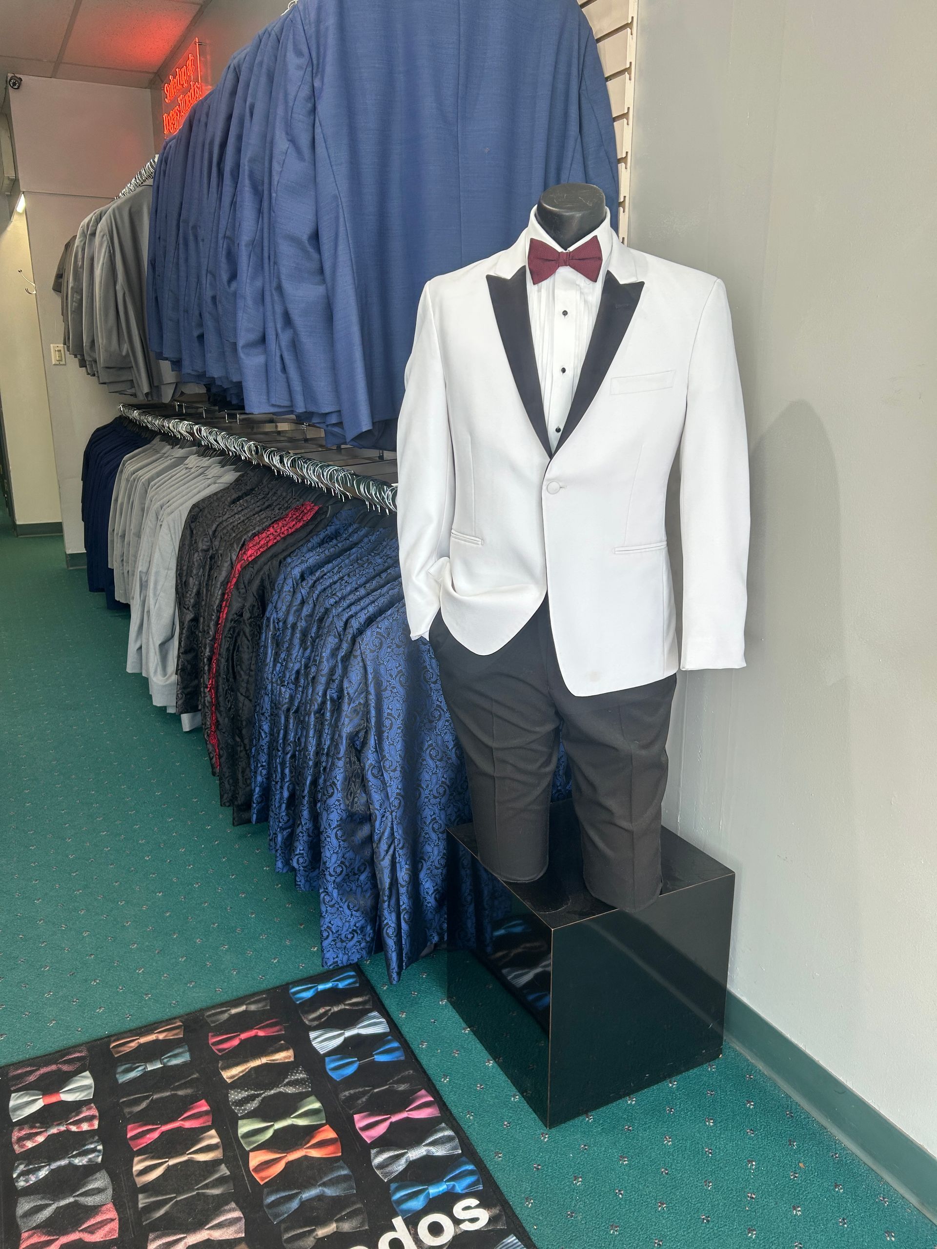 Tuxedo jacket and formal shirts displayed on a shop rack in a store hallway