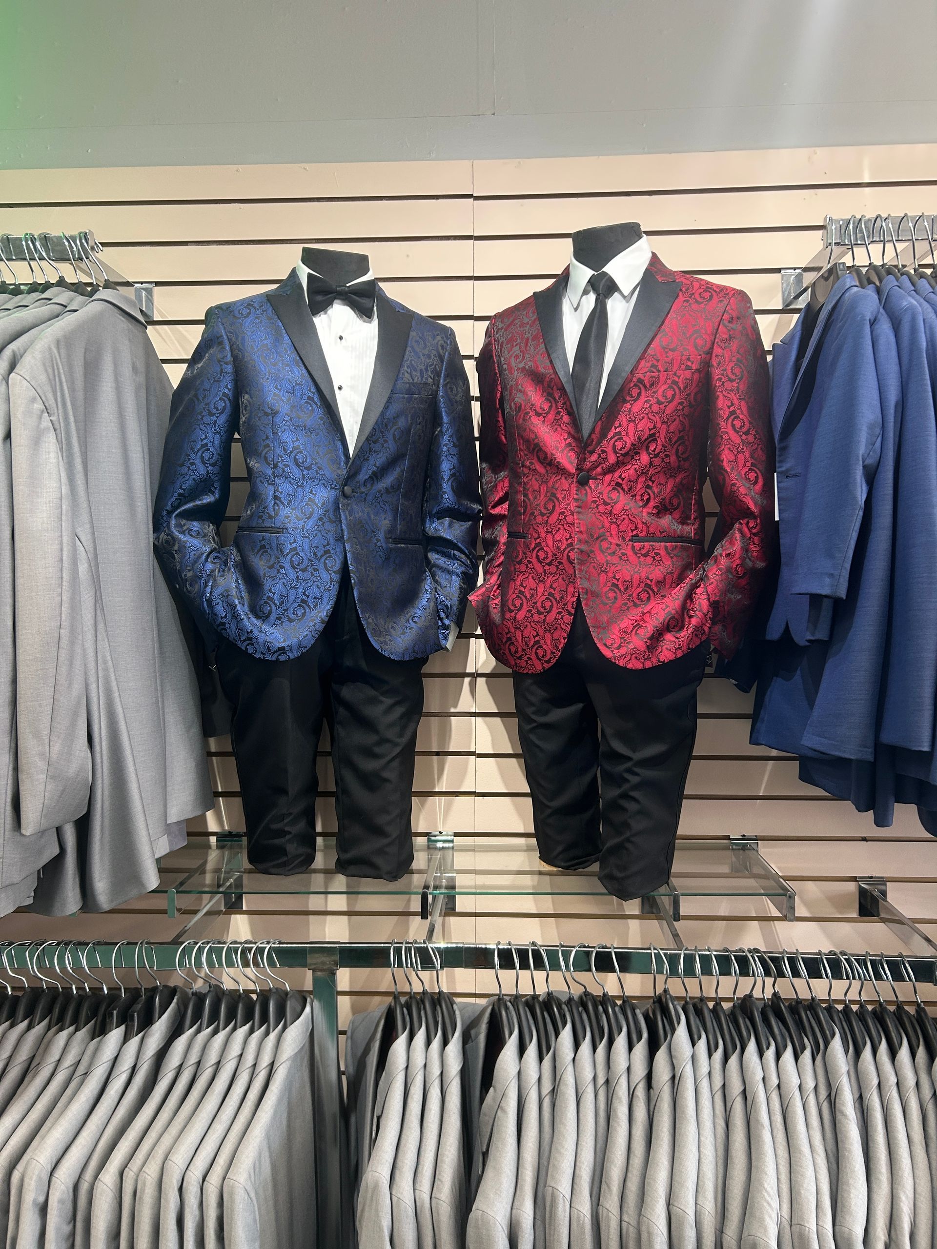 Men’s formal suits displayed on mannequins, including blue and red patterned jackets with black trousers.
