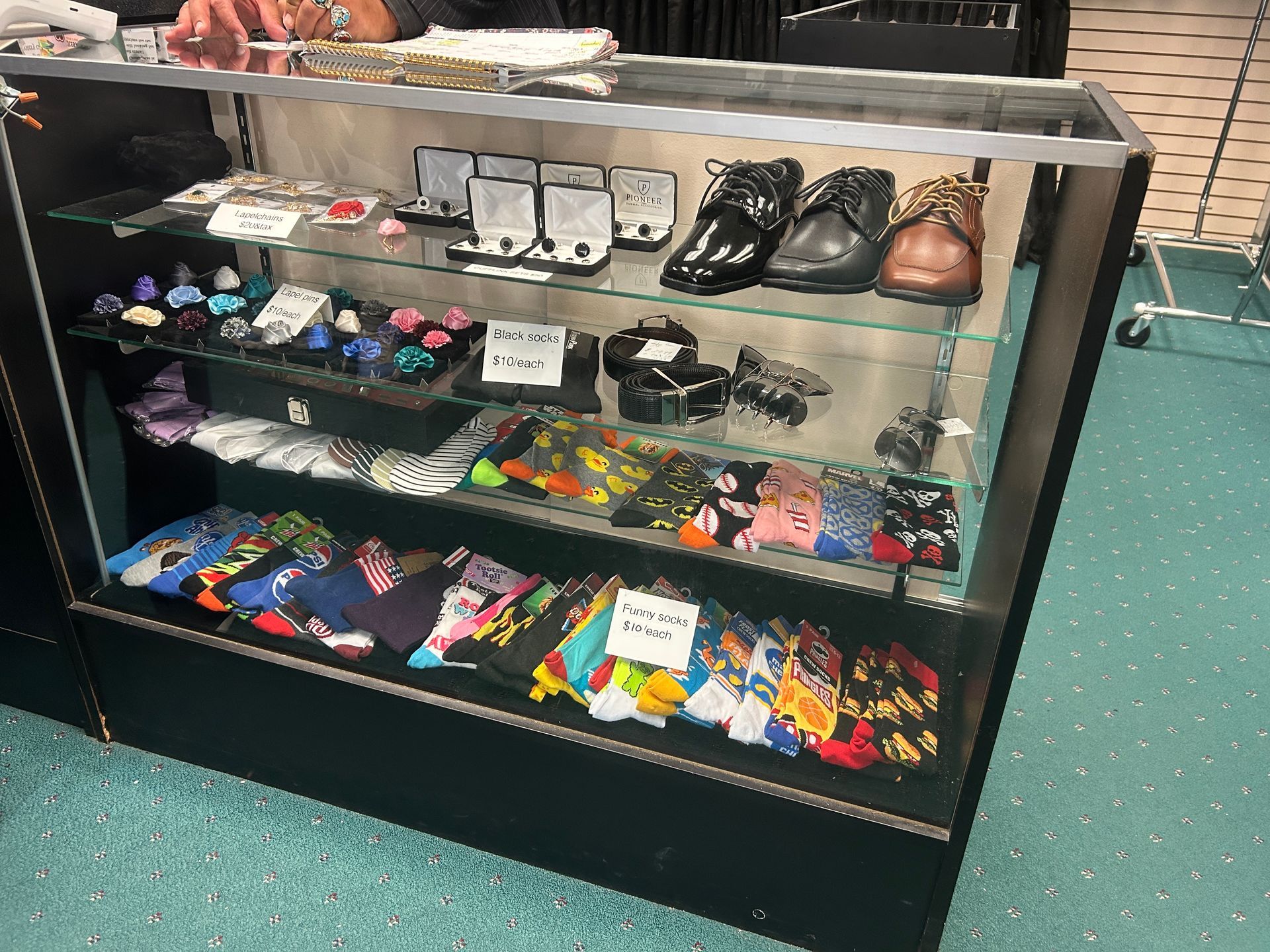 Glass display case with neatly arranged socks, ties, and men’s shoes in a store