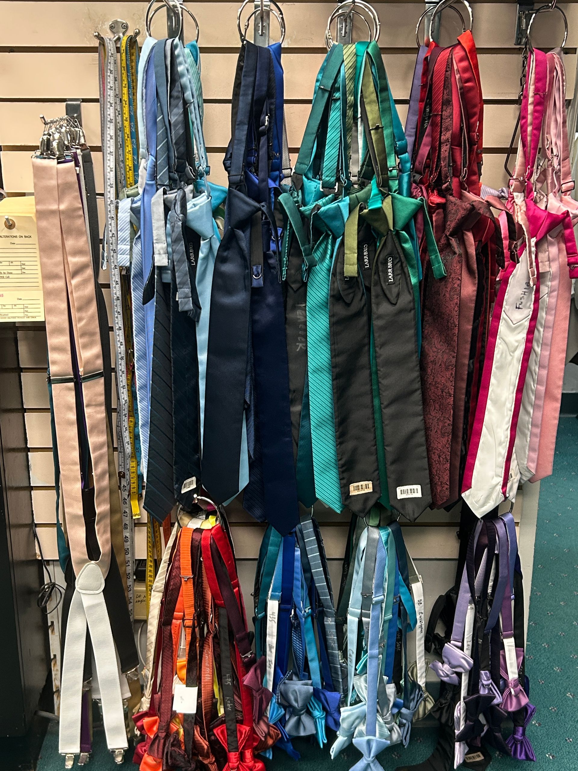 Colorful hanging straps and leashes displayed on a store wall, in blue, teal, pink, purple, and black.