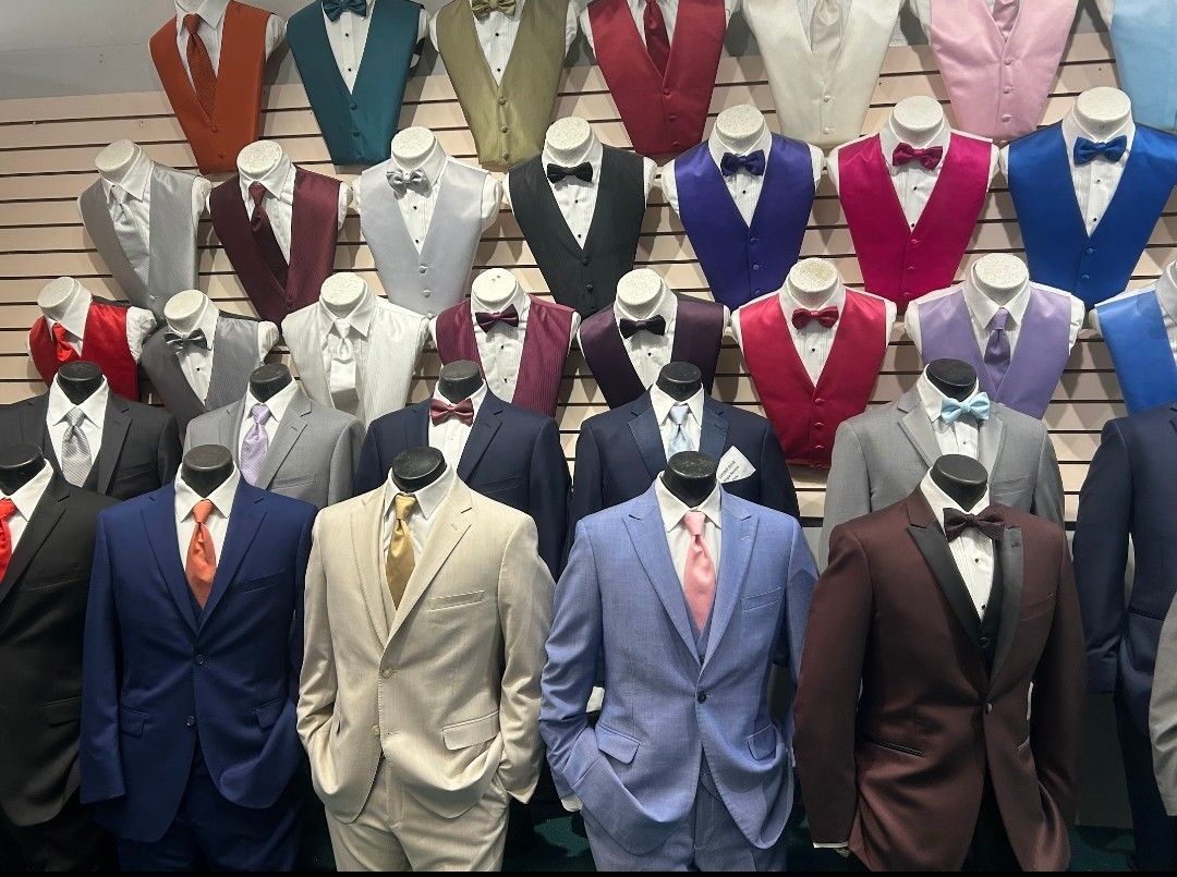 Row of mannequin torsos displaying colorful suit jackets and vests on a shop wall