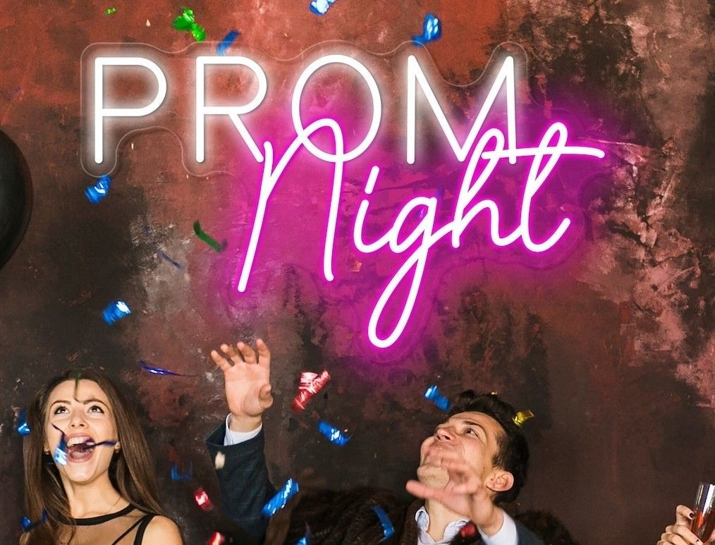 Neon “PROM Night” sign above smiling guests tossing confetti at a party