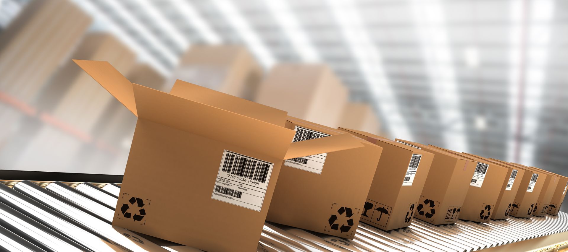 Row of cardboard boxes with barcodes moving along a conveyor in a warehouse.