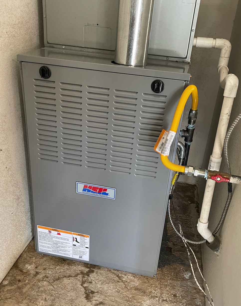 A gas furnace is sitting next to a water heater in a room.